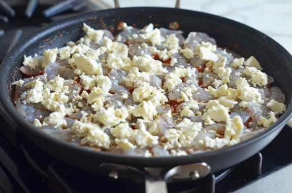 Feta atop shrimp in tomato sauce.