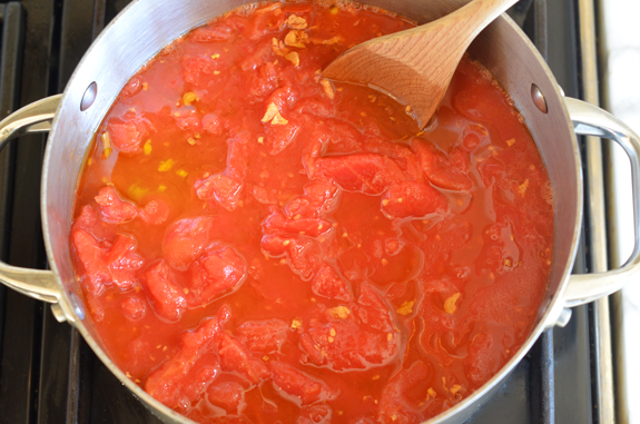 Wooden spoon in a pan of tomatoes.