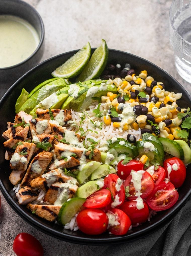 burrito bowl with green sauce and glass of water on side