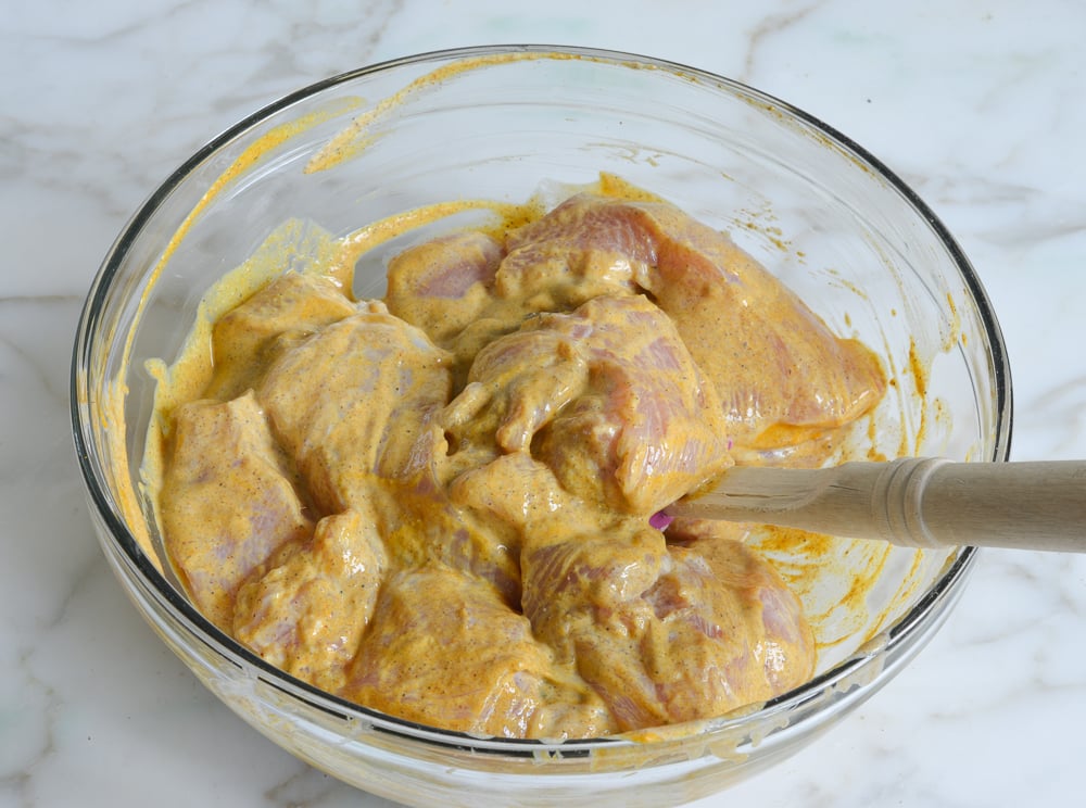 mixing raw chicken with yogurt marinade 