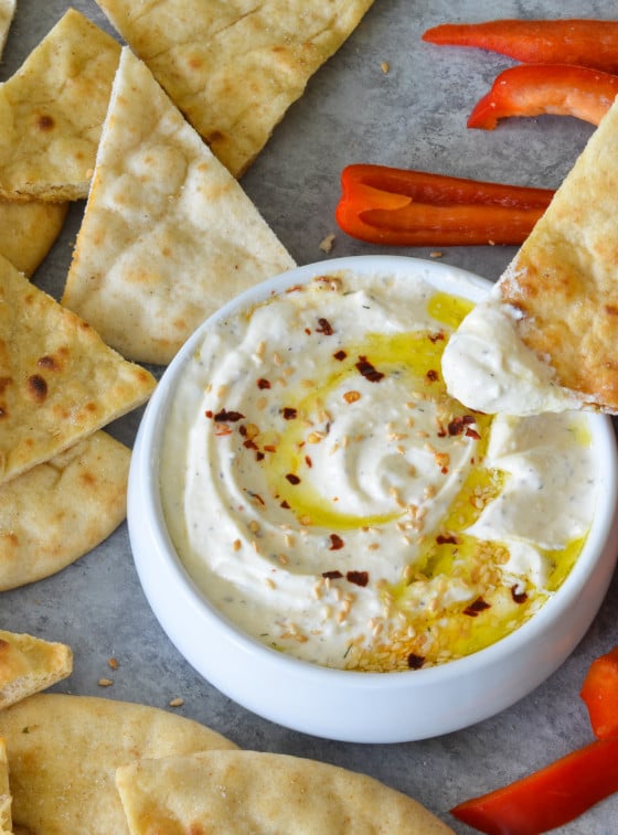 Person dipping bread into feta dip.