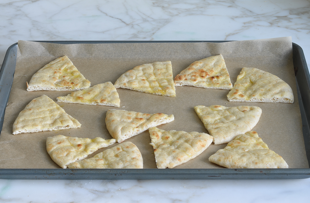 Pita wedges on a lined baking sheet.