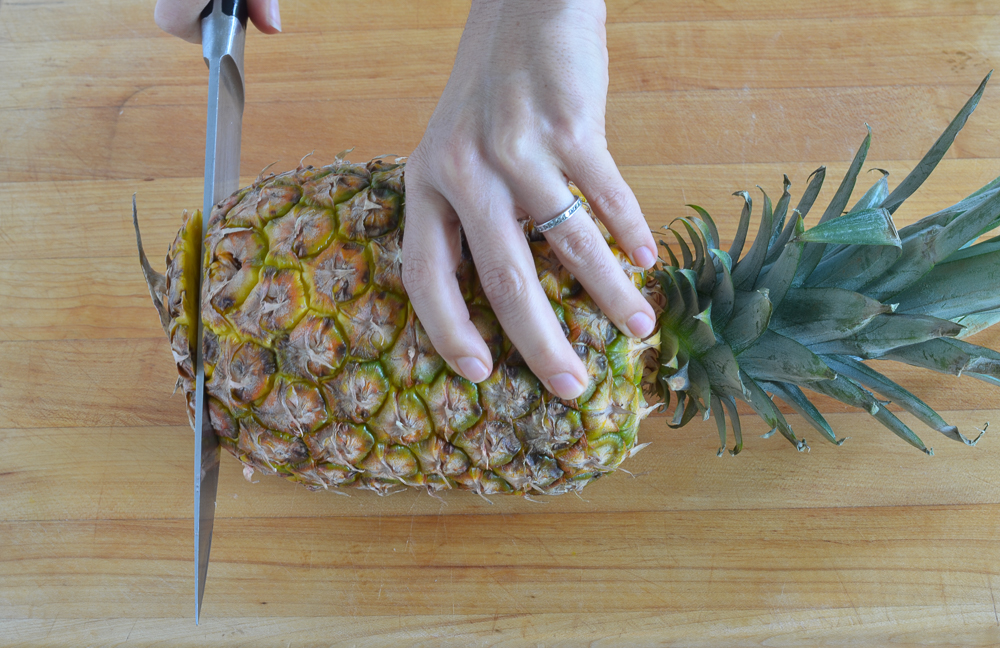 slicing off bottom of pineapple