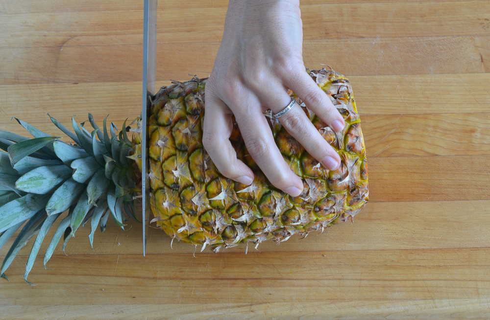 slicing off top of pineapple