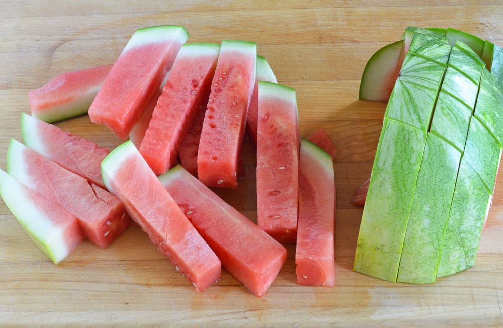 Sticks of watermelon on a cutting board.