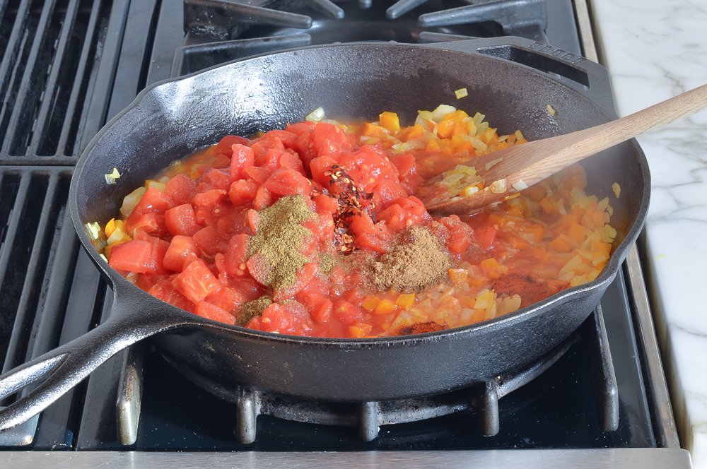 Adding the tomatoes and spices to the skillet
