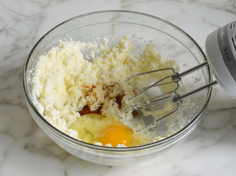 Vanilla and eggs in a bowl of creamed butter and sugar.