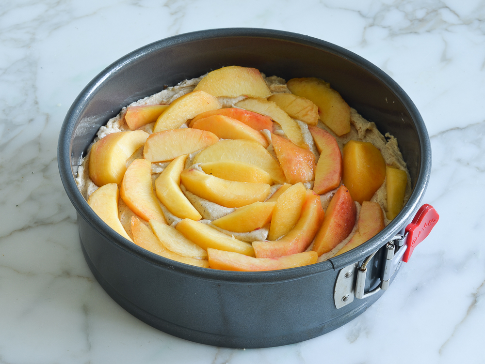 Layer of peach slices over cake batter in a springform pan.