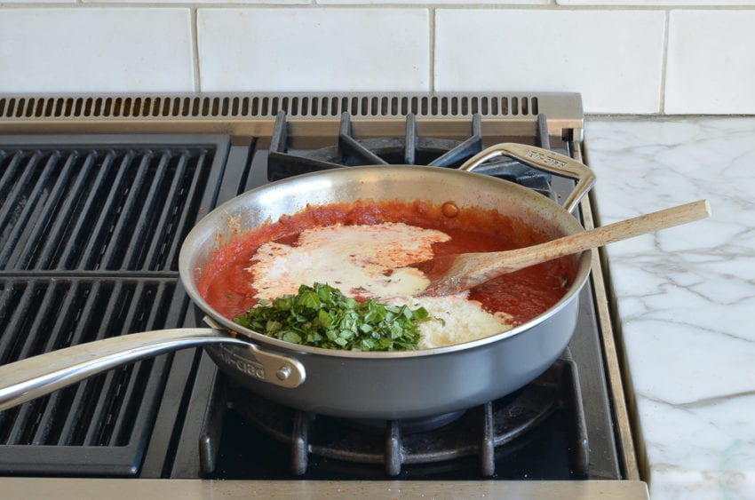 cream and basil added to tomato sauce in skillet