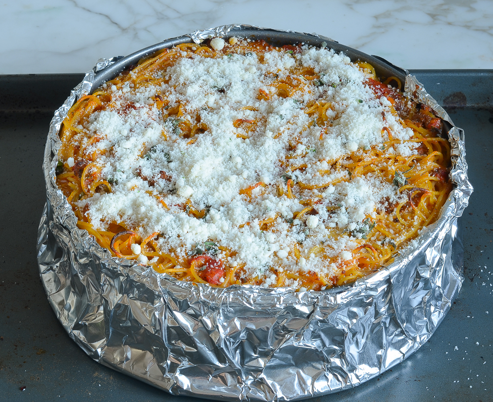 Spaghetti pie topped with parmesan cheese.