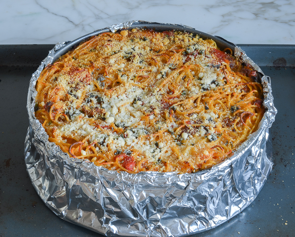 Aluminum foil-wrapped pan of spaghetti pie.