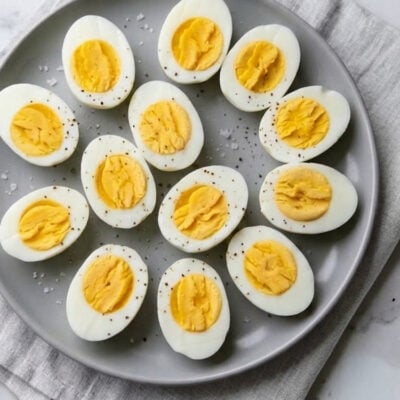 Halved hard-boiled eggs arranged on gray platter.