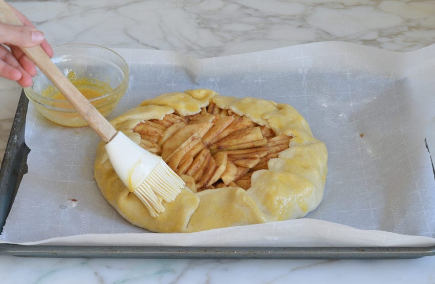 Brush adding beaten egg to pastry dough.