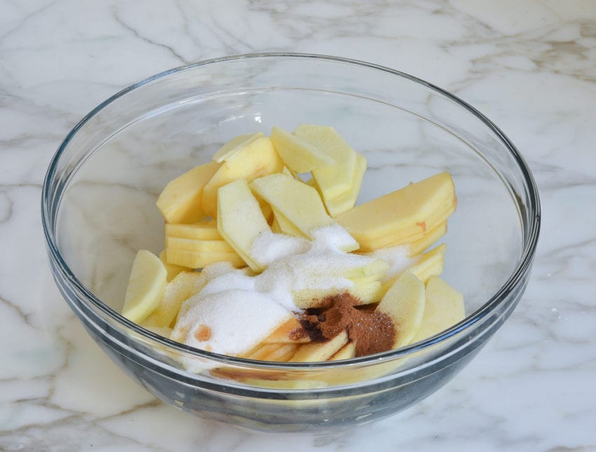 Apple slices in a bowl with sugar.