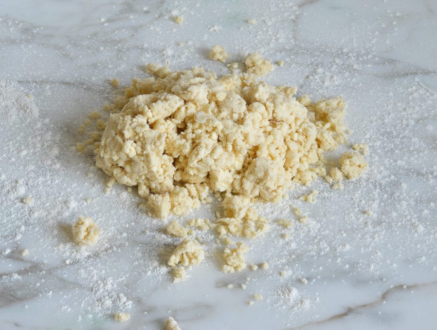 Pile of crumbly dough on a counter top.