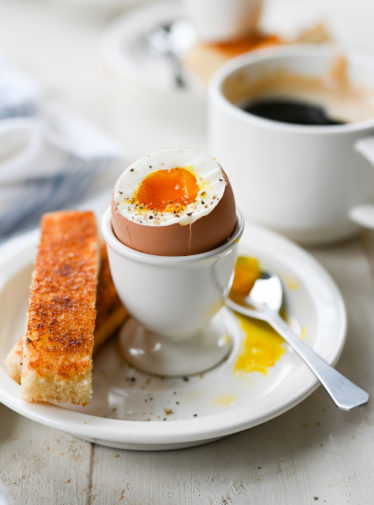 Soft-boiled egg with the top removed in an egg cup.