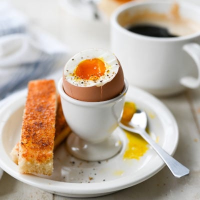 Soft-boiled egg with the top removed in an egg cup.