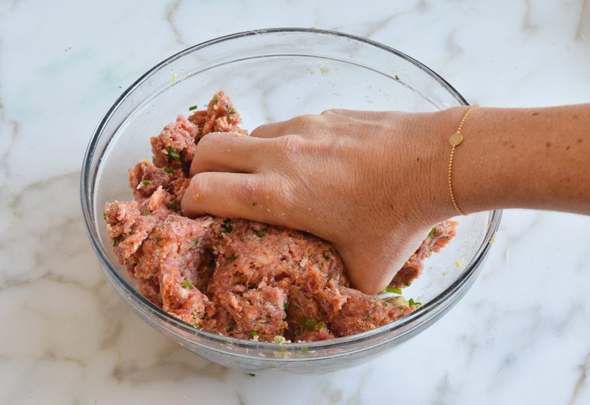 Person mixing meatball mixture by hand.