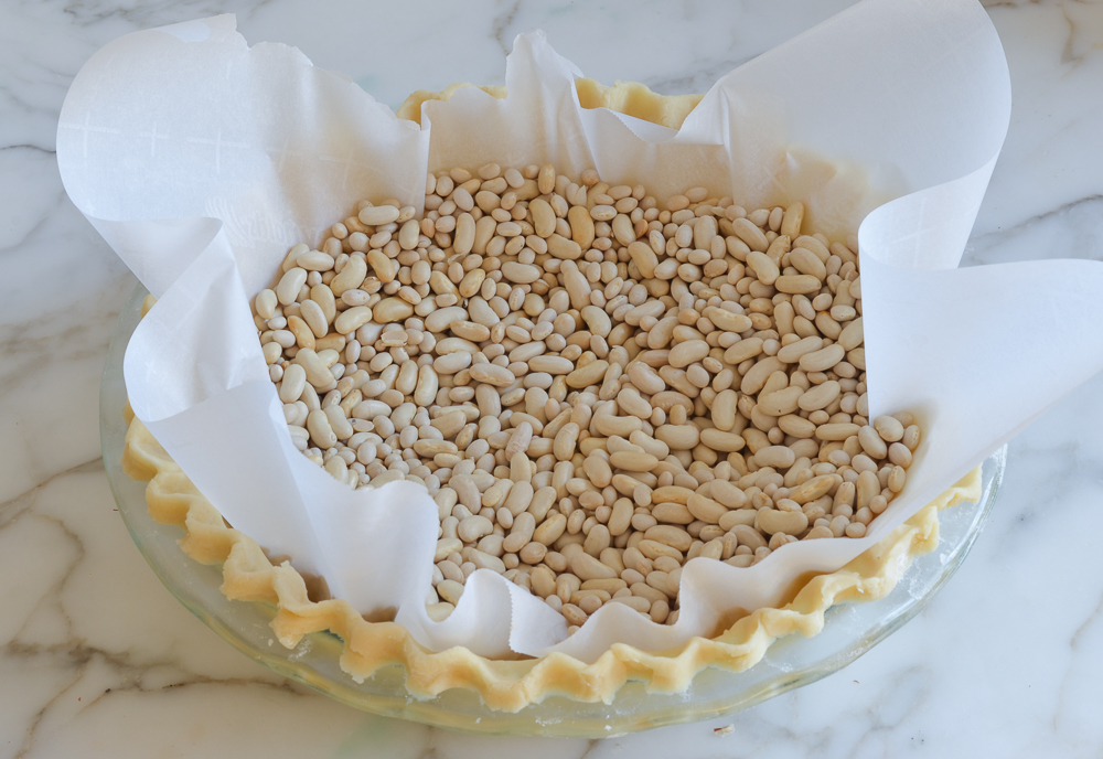 Lined pie crust filled with dry beans.