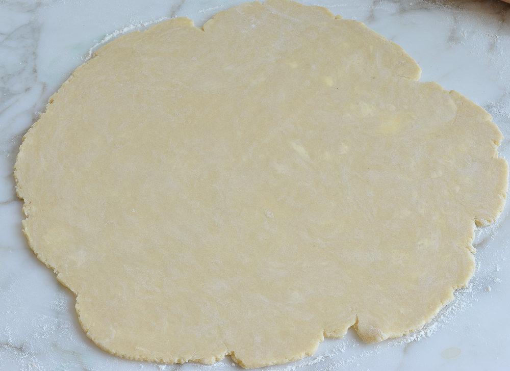 Circle of dough on a marbled surface.