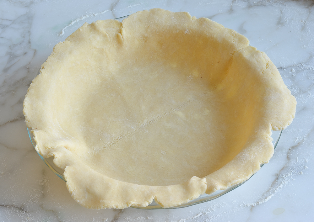 Rough-edged circle of dough in a pie pan.