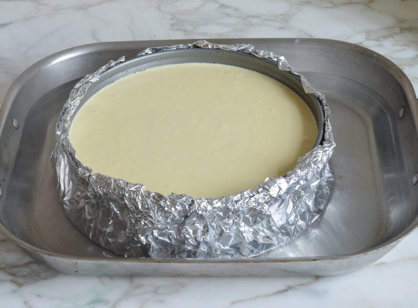 Springform pan of cheesecake on a baking sheet.