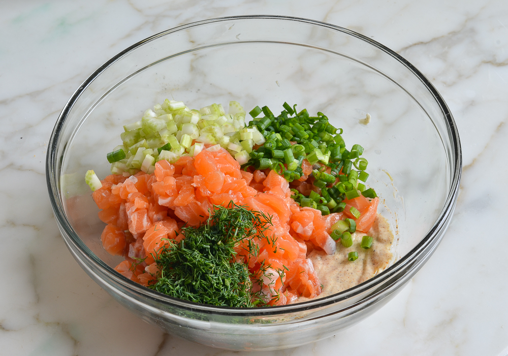 chopped salmon, herbs and sauce in mixing bowl