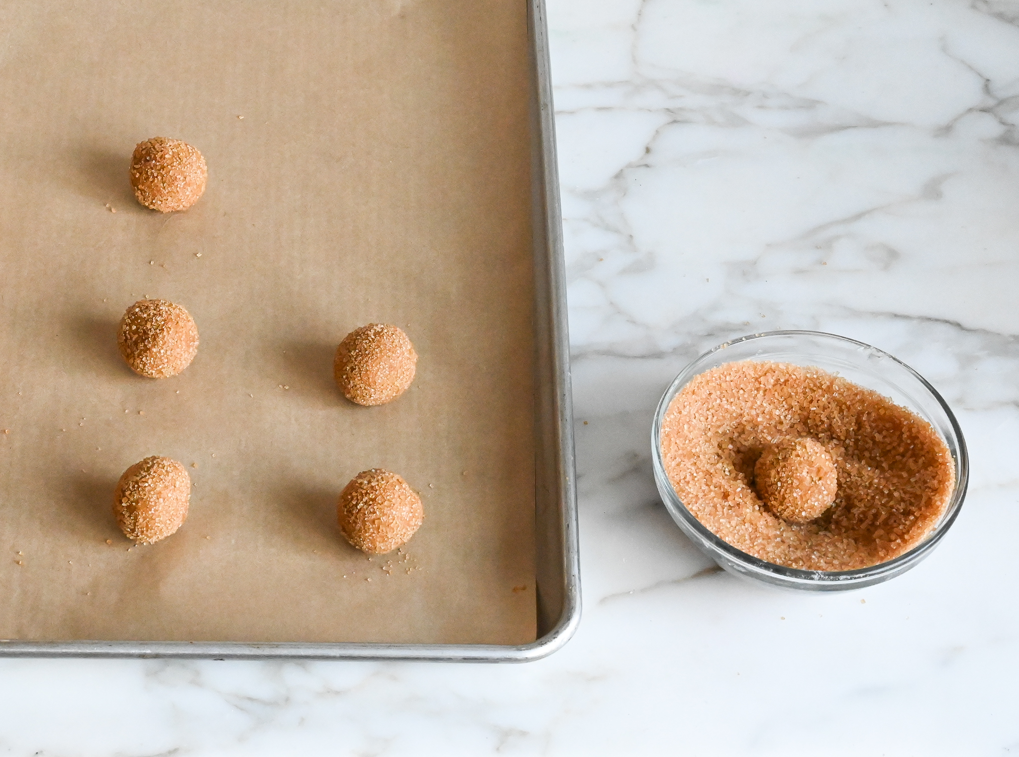 rolling molasses cookie dough balls in sugar