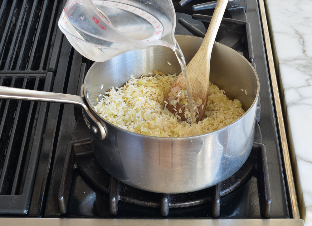 Water pouring into a sauce pan of rice.