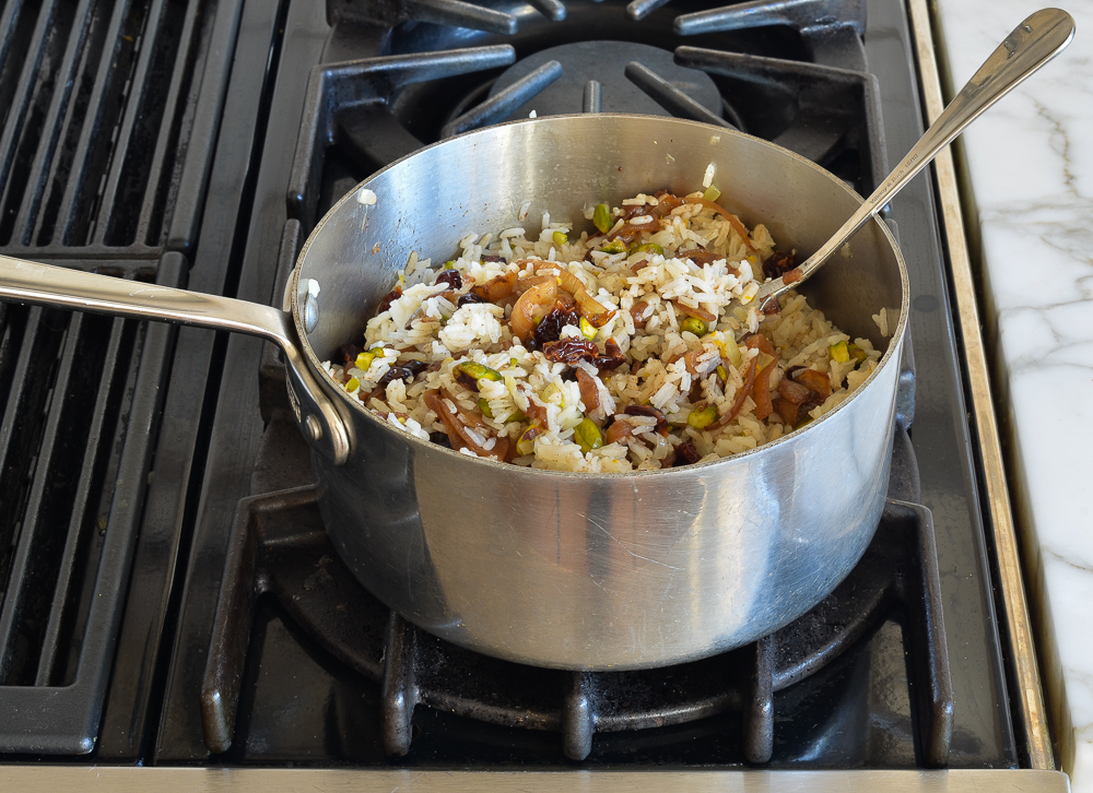 Saucepan of rice pilaf with caramelized onion, orange, cherry, and pistachio.