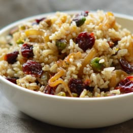 Bowl of rice pilaf with caramelized onion, orange, cherry, and pistachio.