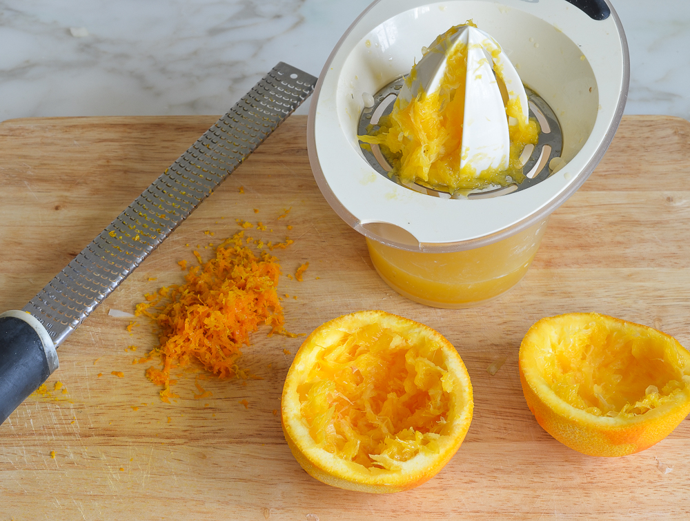 Orange zest and juice on a cutting board.