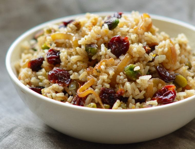 Bowl of rice pilaf with caramelized onion, orange, cherry, and pistachio.