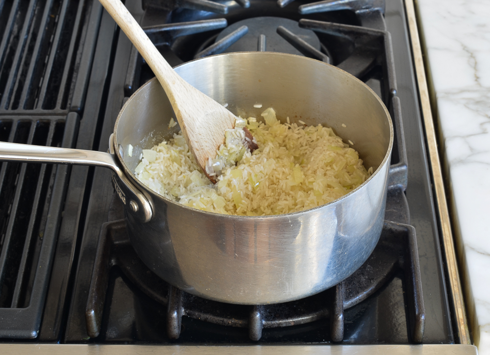 Rice in a sauce pan with onions.
