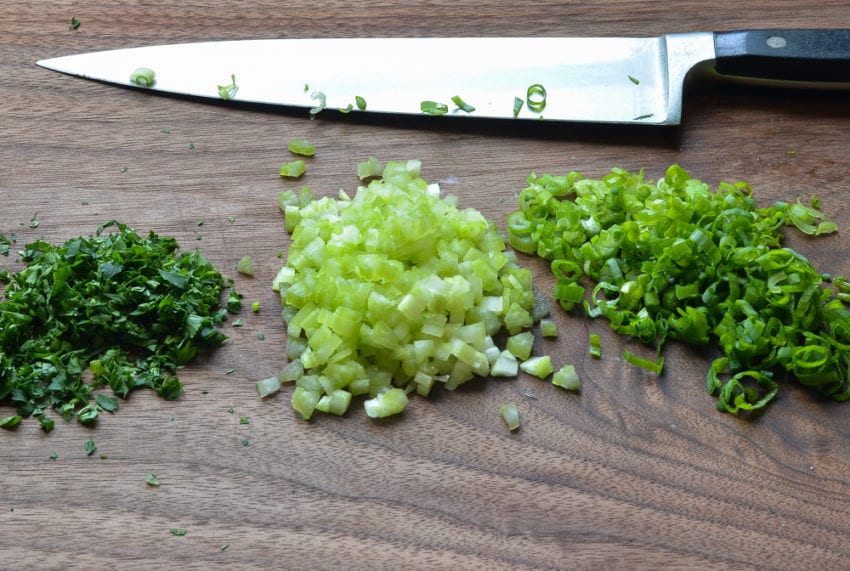 chopped parsley, celery and scallions on cutting board