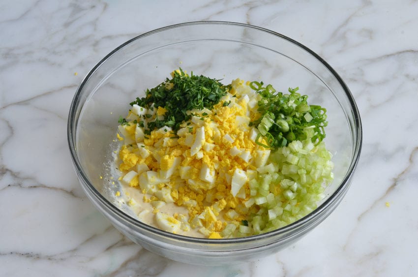 dressing, eggs, and add-ins in mixing bowl