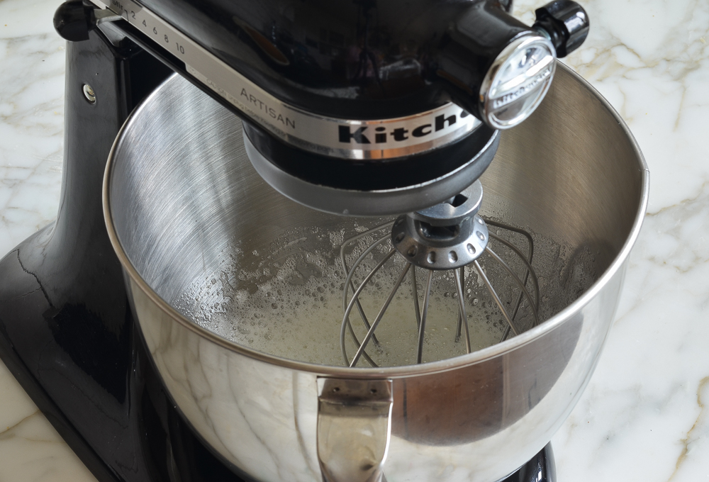 Bowl in a stand mixer with a whisk attachment.