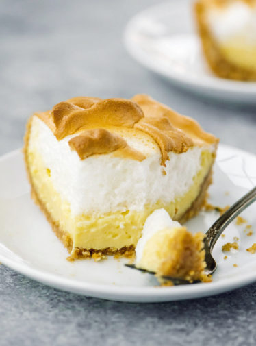 Slice of lemon meringue pie on a plate with a fork.