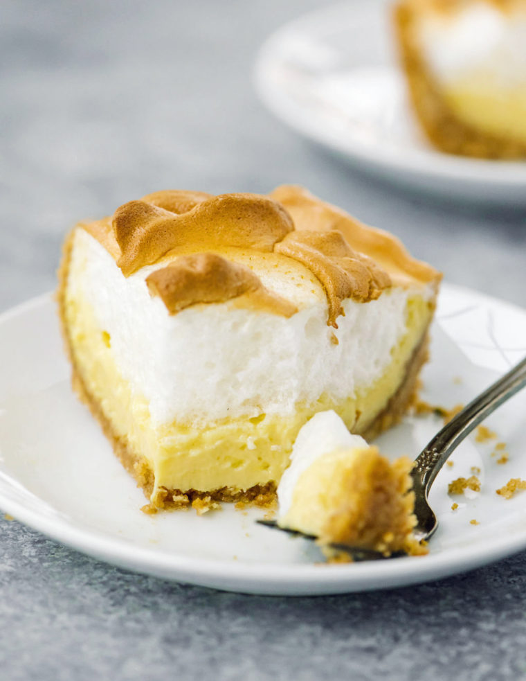 Slice of lemon meringue pie on a plate with a fork.