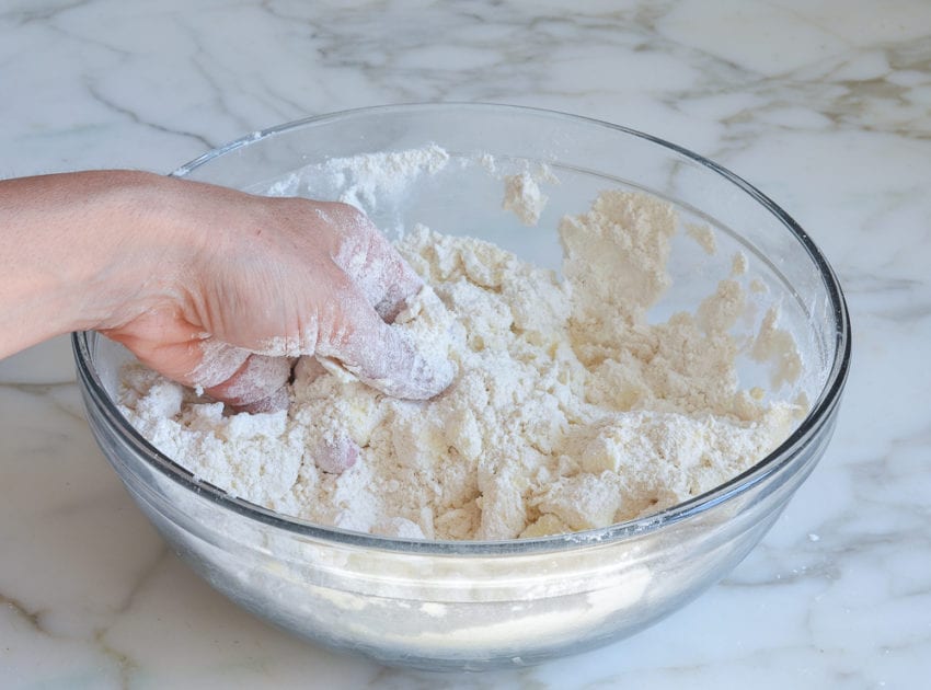 Hand rubbing butter into dry ingredients.