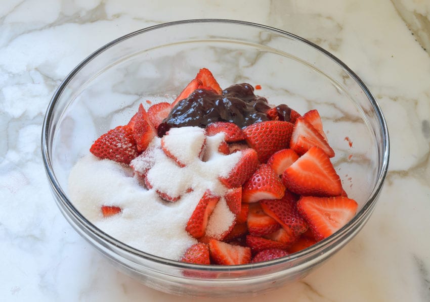 Bowl of unmixed fruit and sugar.