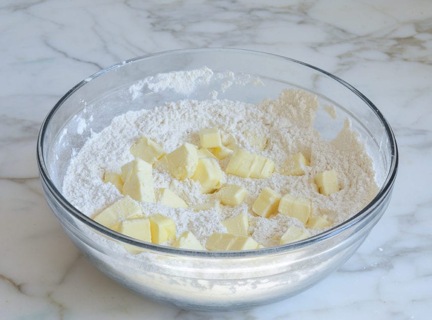 Pieces of butter in a bowl of dry ingredients.