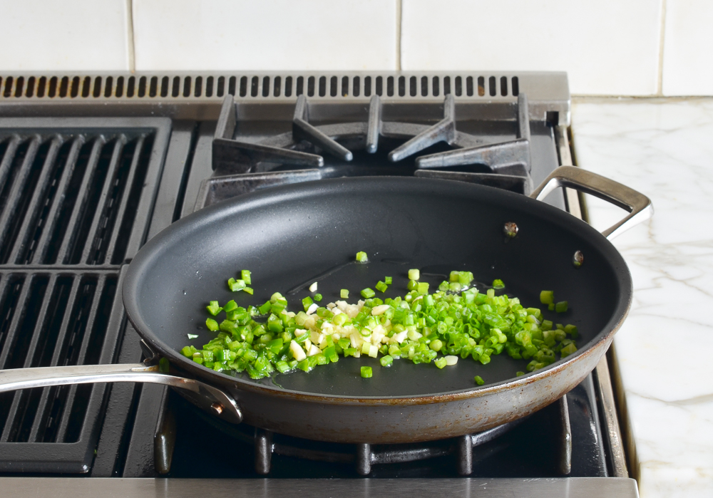 Light scallions, garlic, and jalapeno in a skillet.