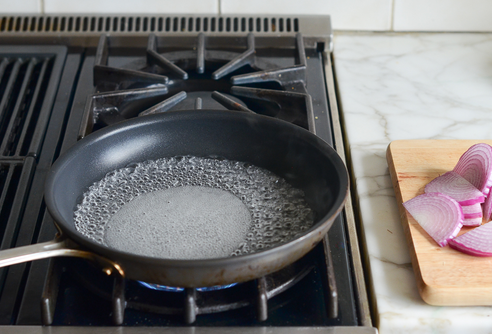Sugar dissolving into liquid in a pan on the stovetop.