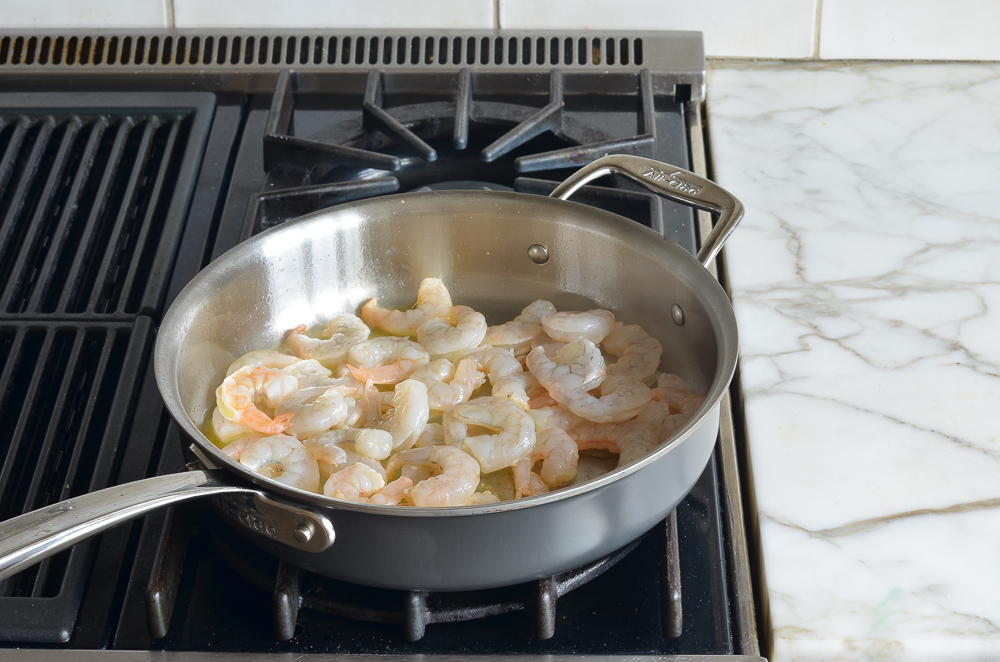 Shrimp cooking in oil on a stovetop.