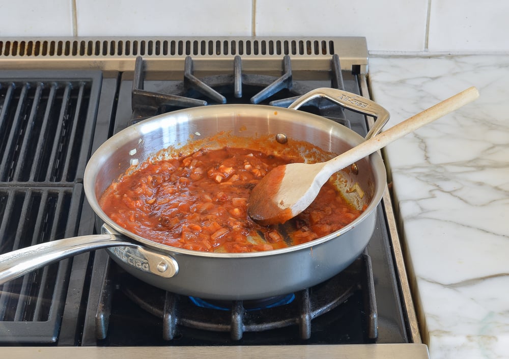 Skillet of simmering sauce on a stovetop.