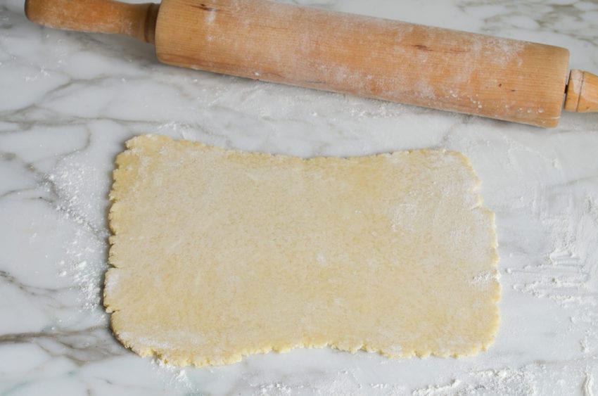 Rolling pin next to rolled dough.