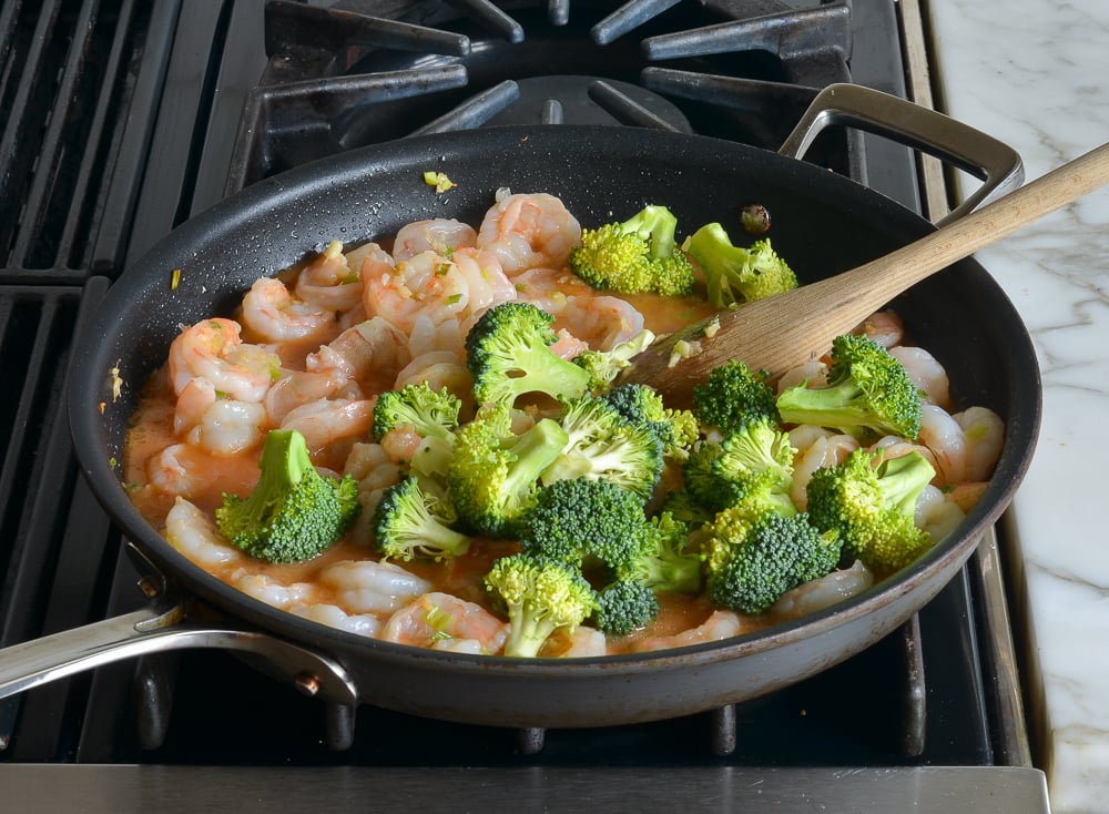 Broccoli in a skillet with shrimp.