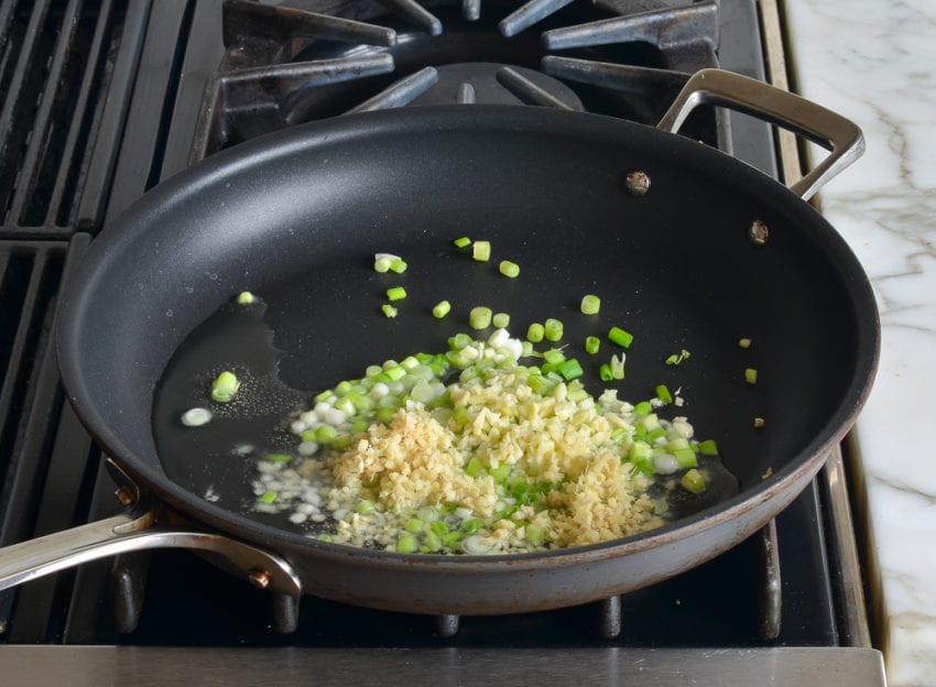 Scallions, ginger, and garlic in a skillet.