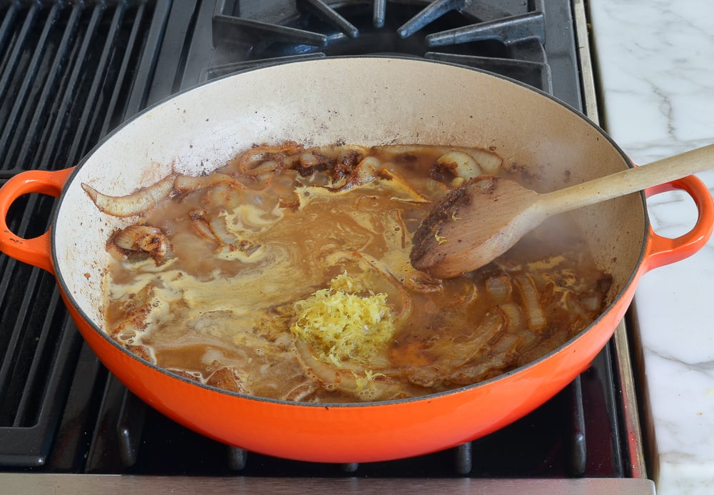 Broth and lemon zest in a skillet with onions.